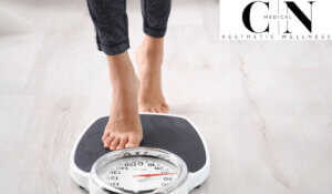 A woman stepping on a weighing scale to check her weight.